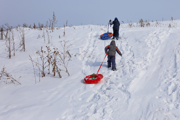 child climb the hill with a tube for descent. Children ride in the winter with slides on tubing. winter leisure