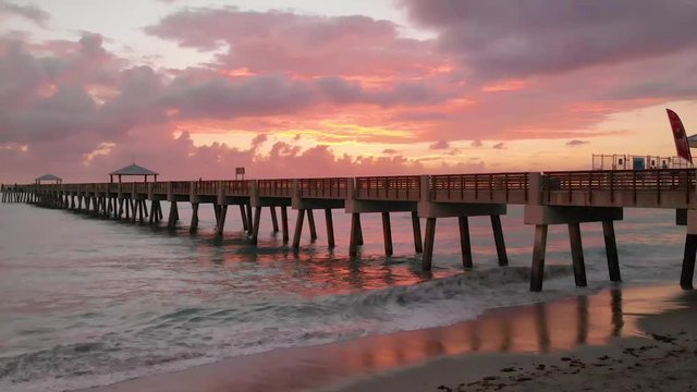 Slow motion aerial crane view of dawn breaking  over the Pier at Juno Beach Florida
