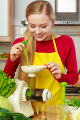 Woman in kitchen making vegetable smoothie juice