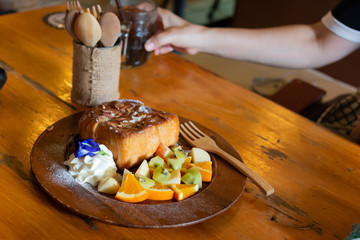 Honey toast Topped with condensed milk with Mixed Fruit on wood table