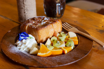 Honey toast Topped with condensed milk with Mixed Fruit on wood table