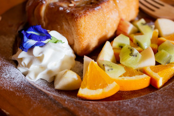 Honey toast Topped with condensed milk with Mixed Fruit on wood table
