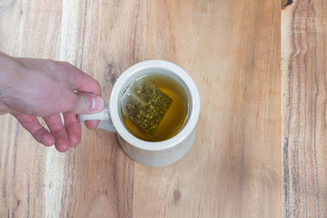hand holding cup of tea on wood table