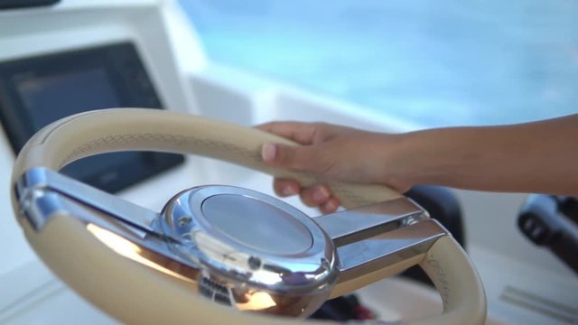 Close-up captain hand on white leather steering wheel of party boat, the captain drives the luxury yacht