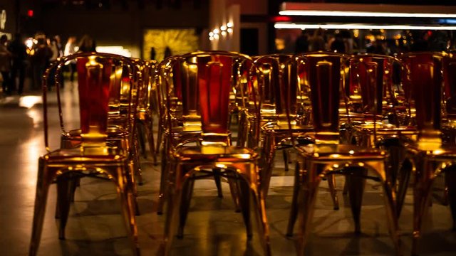 Tracking shot of the first row of many empty shiny golden chairs.