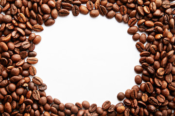 Roasted brown coffee beans scattered on white table with a lot copy space for text. Flat lay composition. Close up, top view, background.