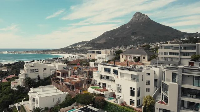 Slow descending drone shot of Lions head mountain with fancy beach houses in the foreground