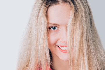 Naklejka premium Close-up portrait of beautiful cute blonde woman with long hair, clean skin, natural makeup, and white teeth