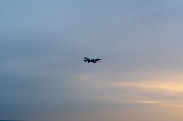 A airplane flying in the sky at sunset
