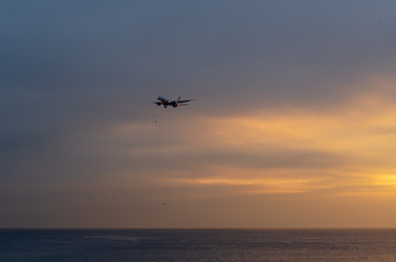 Naklejka na ściany i meble A airplane flying in the sky at sunset