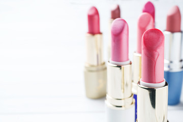 Set of colored pink lipsticks on white background. Women's cosmetics. Selective focus. Copy space.