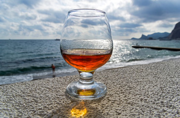 A glass of cognac on the background of the sea.