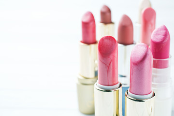 Obraz premium Set of colored pink lipsticks on white background. Women's cosmetics. Selective focus. Copy space.