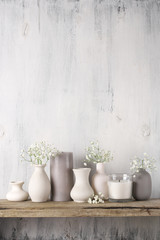 White flowers in neutral colored vases and candles - obrazy, fototapety, plakaty