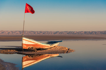 old thrown boat on the bottom of the dry salty lake Chott el Djerid in Tunisia