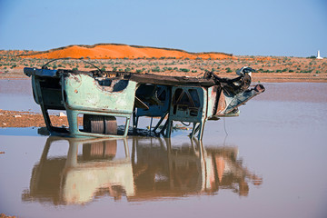 .rusty inverted car in the puddle after the flood in the desert of tunisia