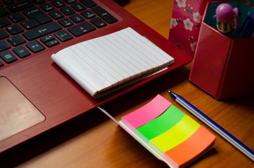 home office desk, red laptop, coffee, notebooks, diary, pen