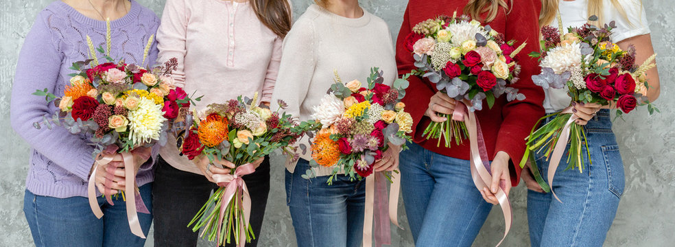 Florist workplace. Woman arranging a bouquet with roses, chrysanthemum, carnation and other flowers. A teacher and students of floristry in master classes or courses