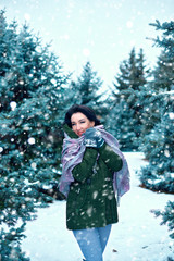 beautiful woman is in winter forest, green fir trees with snow