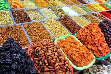 Dates, dried apricots, prunes against the background of various nuts almonds, hazelnuts, walnuts, cashews in blur.