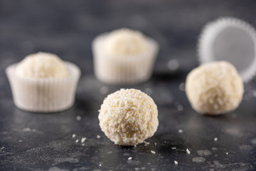 Fototapeta na wymiar White chocolate candy coconut truffles on a dark background. homemade candies with coconut flakes.