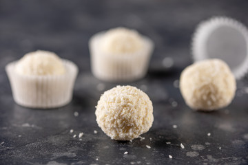 White chocolate candy coconut truffles on a dark background. homemade candies with coconut flakes.