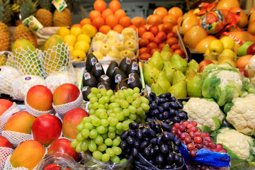 Green black red berries of grapes, mango, pears, apples, pineapple, melon are on the market for sale
