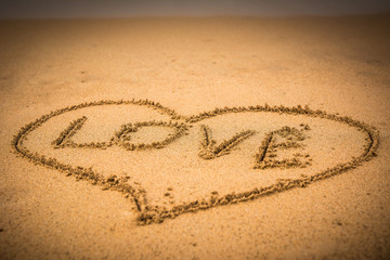 love written on beach sand with heart