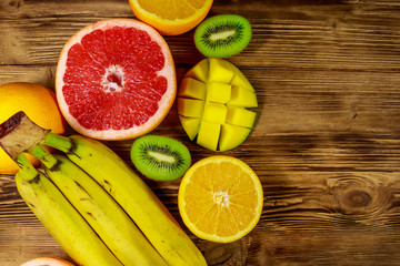 Assortment of tropical fruits on wooden table. Still life with bananas, mango, oranges, avocado, grapefruit and kiwi fruits