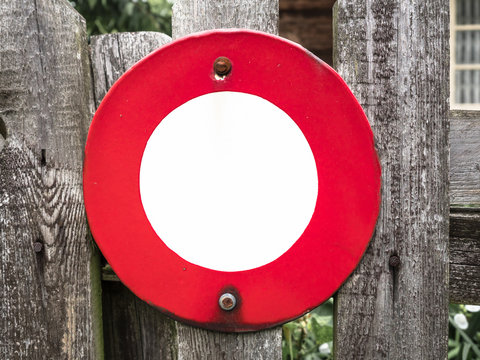 Signboard side view of empty white mock up red circle signage with old wooden gate background display exterior. Medieval, middle age style with artistic metal blacksmithing decoration
