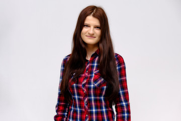 Fototapeta premium Concept studio portrait of a beautiful young beautiful brunette girl on a white background with different emotions in a multi-colored shirt.