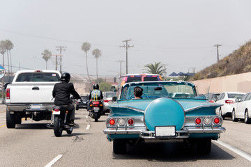 A traffic jam in Malibu, California with a vintage convertible car, motorcycle and pick up truck in...