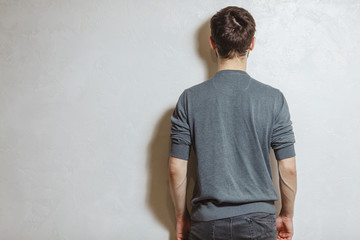 Back view of young man, over white textured background.