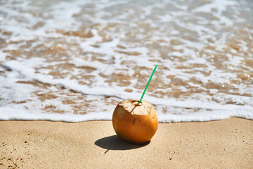 young coconut with a straw lies on the ocean