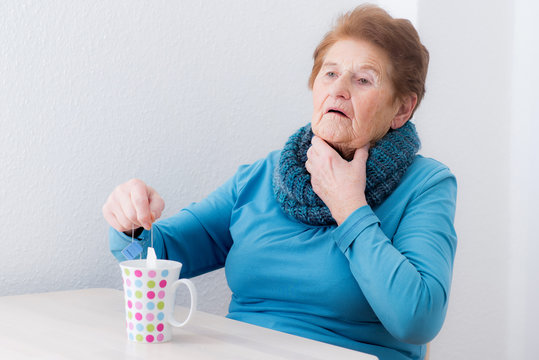 Frau hat Halsschmerzen und macht sich einen Tee