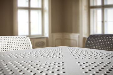 White table background and two chairs with background of window. 