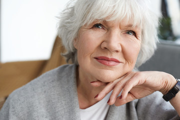 Close up portrait of beautiful positive middle aged Caucasian lady on retirement daydreaming at...