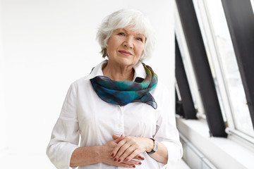 Isolated view of successful positive beautiful businesswoman with gray hair standing in confident...