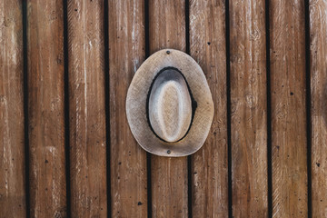 Straw summer hat hanging from wooden wall