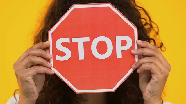 Biracial girl holding stop sign, protesting bullying or racism, gun violence