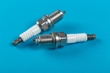 A set of new spark plugs a blue background.