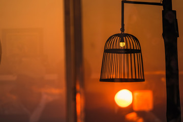 Silhouette Bird cage decorated as outdoor light post with the evening sun in sunset time.Thailand.