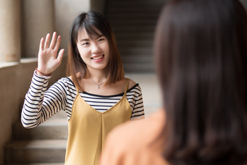 Friendly Asian woman friend greeting  portrait of Happy smiling glad friendly asian female friend saying hi or hello with good relationship  young adult asian woman model © 9nong