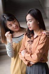 Asian woman getting encoragement from her friend; portrait of good friend cheering up, caring for her sad, unhappy friend