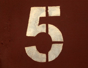 Number 5 in stencil on metal wall.