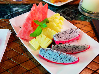 Tropical fruits assortment on a white plate, pineapple, dragon fruit and water melon served on the restaurant
