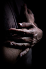 Close up of two men's hands on dark background