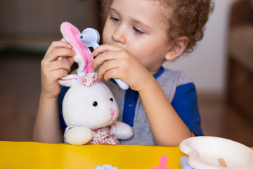 Little boy plays doctor, treats a teddy bunny