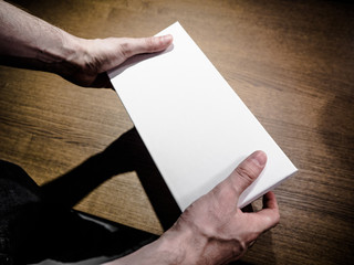 A man (male) two hands hold a empty (blank, vacant) paper box, mock up white box, side view.