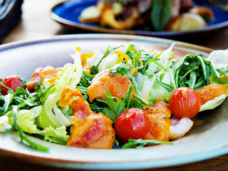 Fresh Shrimps, Mango salad with lettuce green mix, cherry tomatoes, herbs and olive oil, lemon mango dressing. healthy food on wooden table with blurry background in the restaurant 